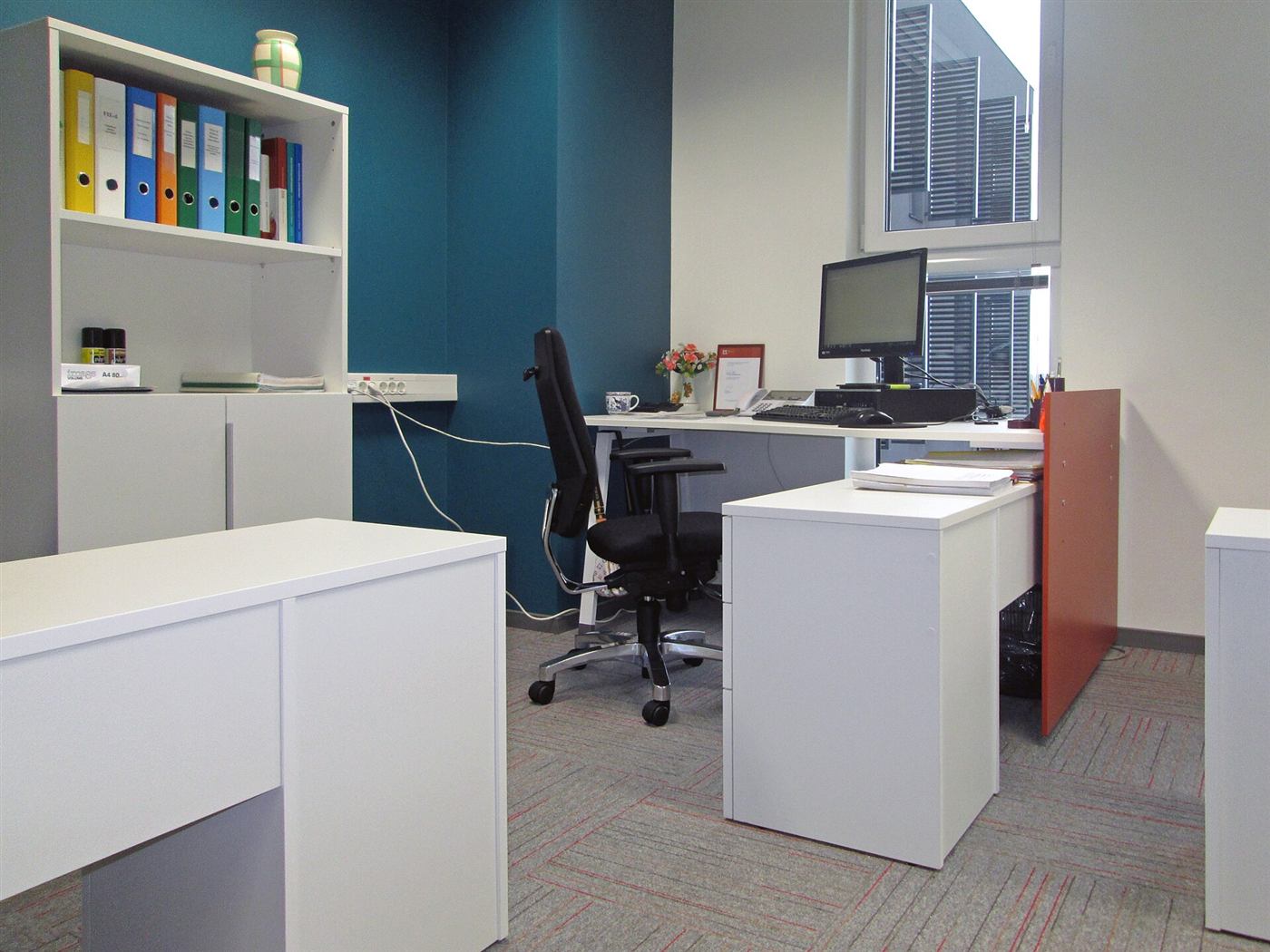 A tidy office with a desk, a chair and shelves of folders